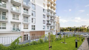 A modern apartment building with multiple balconies, a well-maintained lawn, and a parking area. - Spacious Apartment with a Balcony | Parking (Lublin)