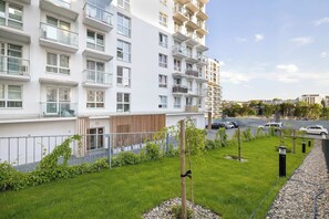 A modern apartment building with multiple balconies, a well-maintained lawn, and a parking area. - Spacious Apartment with a Balcony | Parking (Lublin)