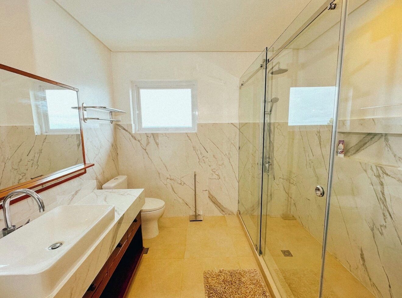 Une salle de bain avec une douche à parois de verre, un lavabo blanc et des toilettes.