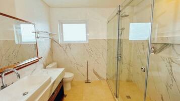 Une salle de bain avec une douche à parois de verre, un lavabo blanc et des toilettes.
