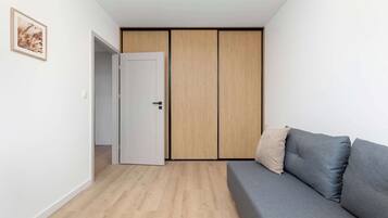 Una habitación moderna con un sofá gris, un armario de madera y una puerta blanca.