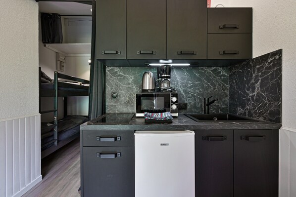 A compact kitchenette with a microwave, coffee maker, and a small refrigerator. - Modern Apartment in Manigod-La Clusaz with Mountain View, Shared Pool & Wi-Fi (Manigod)