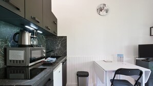 Eine kompakte Küche mit Mikrowelle, Kaffeemaschine und einem kleinen Mülleimer.