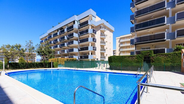 A swimming pool with a metal handrail, surrounded by a paved area and adjacent multi-story residential buildings. - Family Apartments 2 Nova Pineda (La Pineda)