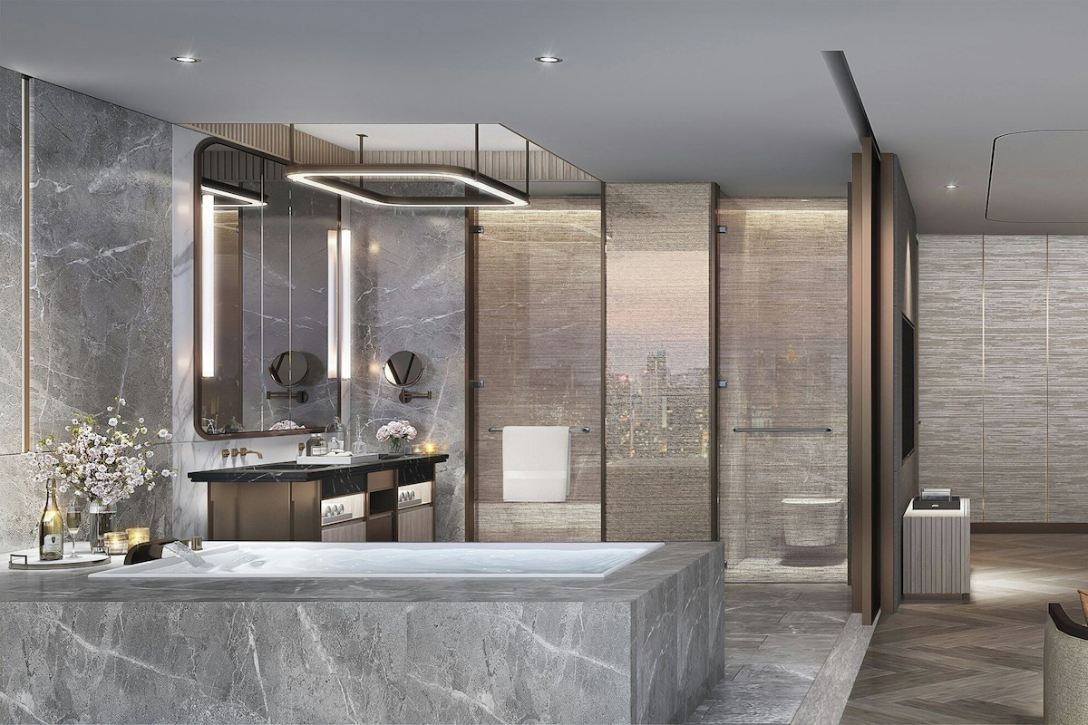 Une chambre d’hôtel moderne avec une salle de bain en marbre, un grand lit, un canapé et une vue sur la ville.