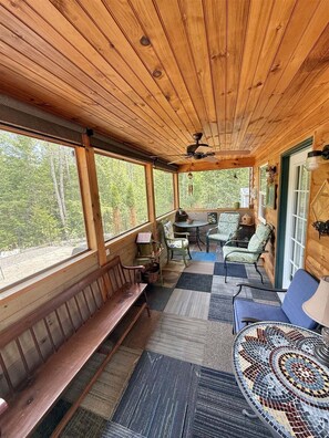 A wooden cabin interior with a bench, chairs, a table, and a patterned rug. - Bald Pate View Limit 6 2 Bedroom Cottage (Sebago)