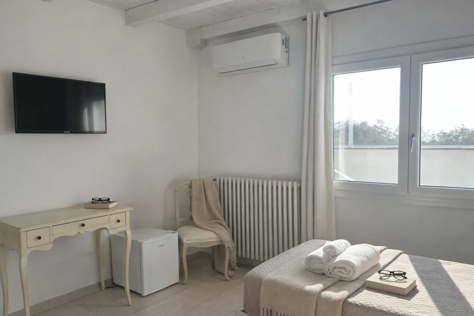 Un dormitorio con cama, escritorio, silla, radiador y televisor.