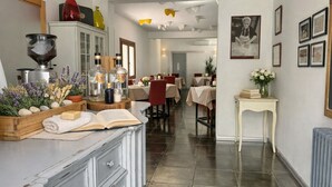 A modern kitchen with a dining area, featuring a coffee machine, bottles, and a book on the counter. - Locanda Divinis (Cerea)