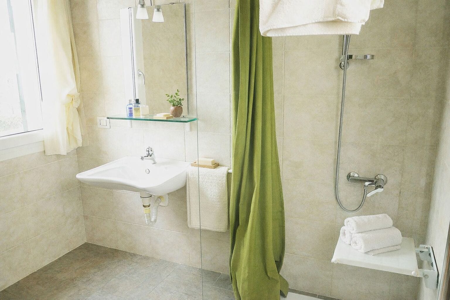 Ein Badezimmer mit Waschbecken, Spiegel, Dusche und einem grünen Vorhang.