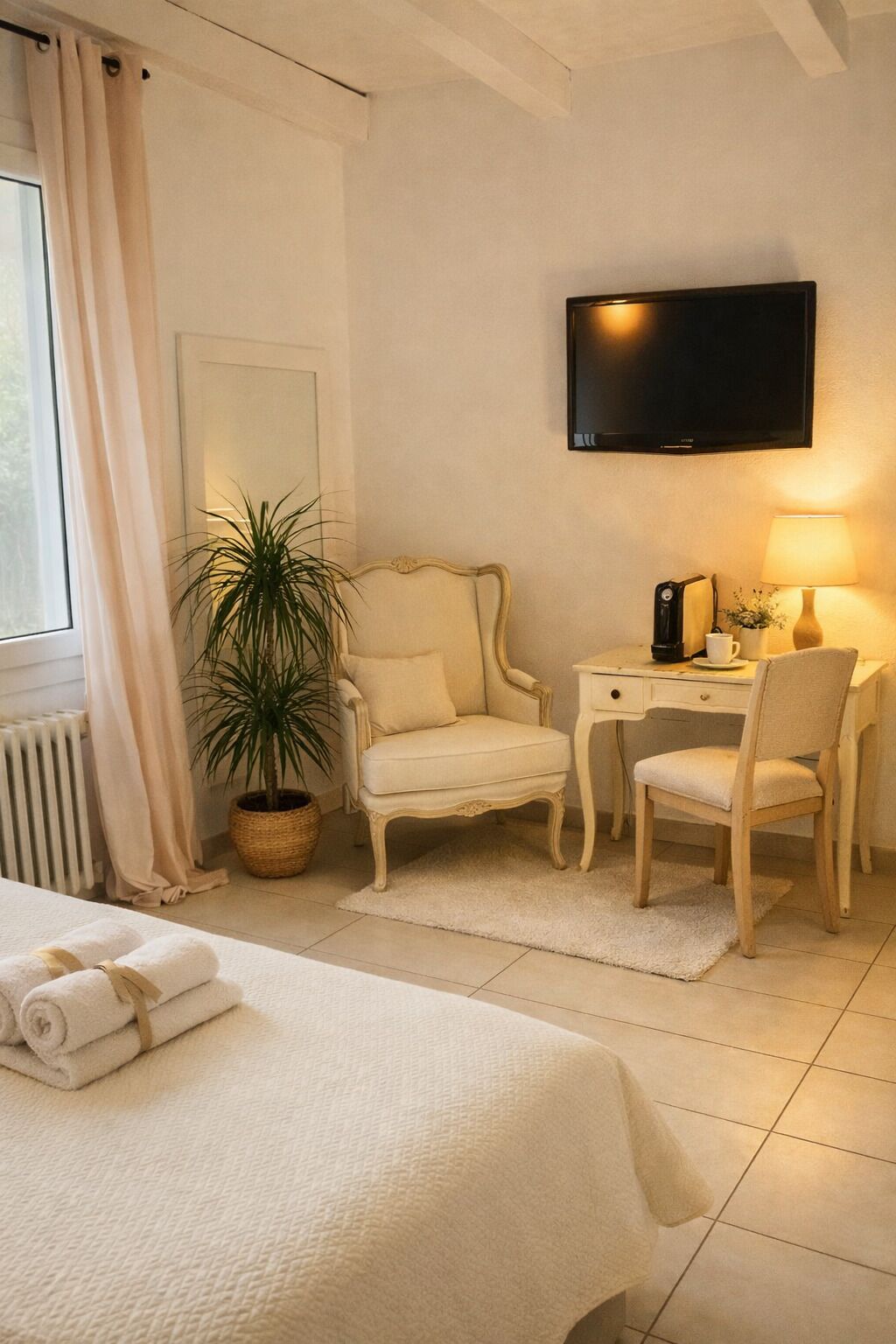 Une chambre d’hôtel avec un lit, un bureau, une chaise, une télévision, une plante en pot et une fenêtre avec des rideaux.