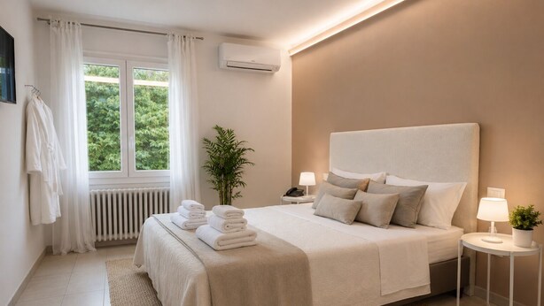 A modern bedroom with a large bed, bedside tables with lamps, a radiator, and a window with curtains. - Locanda Divinis (Cerea)