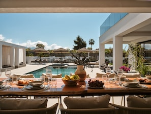 An outdoor dining area with a pool, lounge chairs, and a table set for a meal. - Nosel Villa, a Design Retreat with Iconic Pool (Zakinthos)