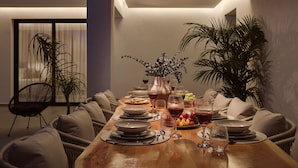 A dining table set with plates, glasses, and a vase of flowers. - Nosel Villa, a Design Retreat with Iconic Pool (Zakinthos)