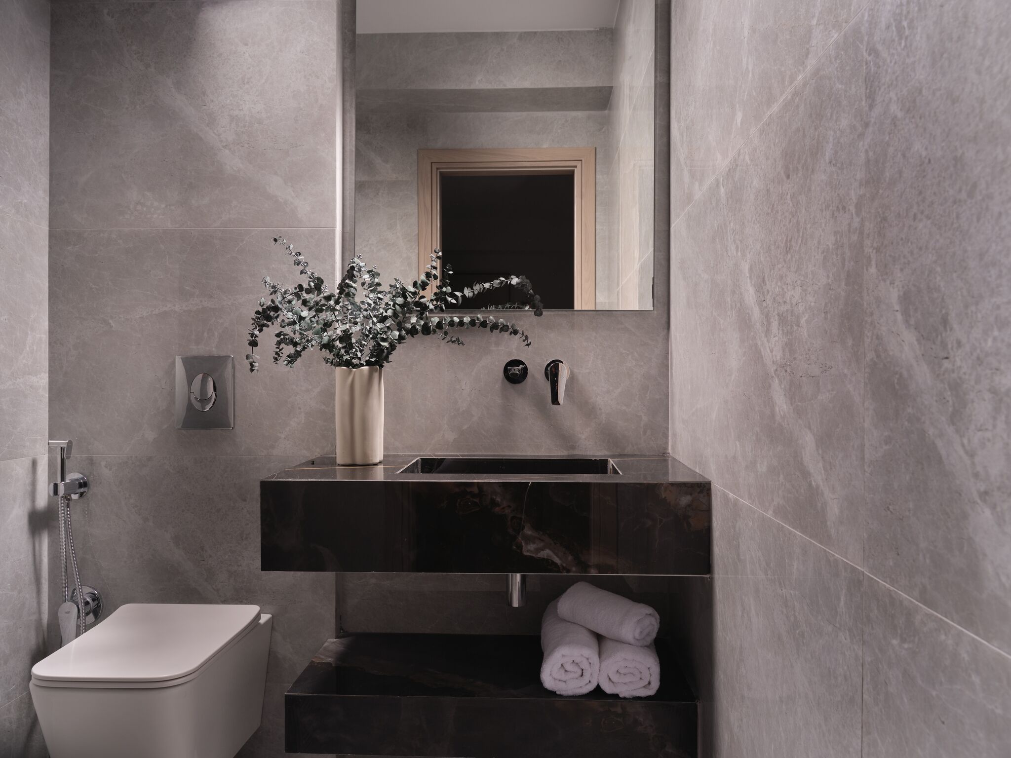 A modern bathroom with a toilet, sink, and towel storage.