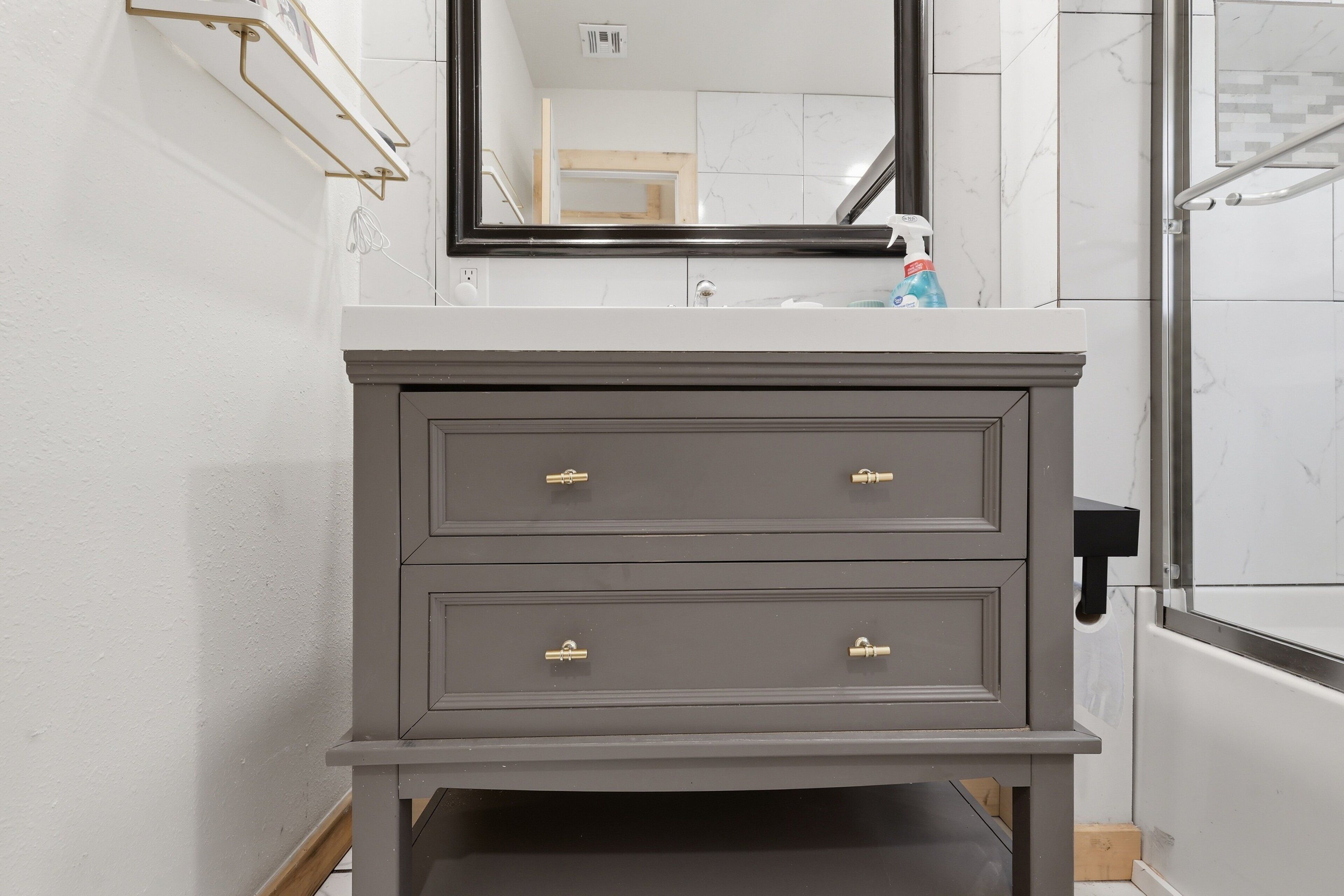 Un mobile bagno con specchio, lavandino e zona doccia.