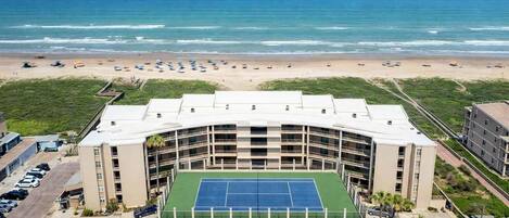 Un hôtel à plusieurs étages doté d’un court de tennis, d’un parking et offrant une vue sur l’océan.