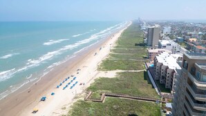 Un hôtel en bord de mer offrant une vue sur la plage, doté de nombreux balcons et bordé d’une longue promenade.
