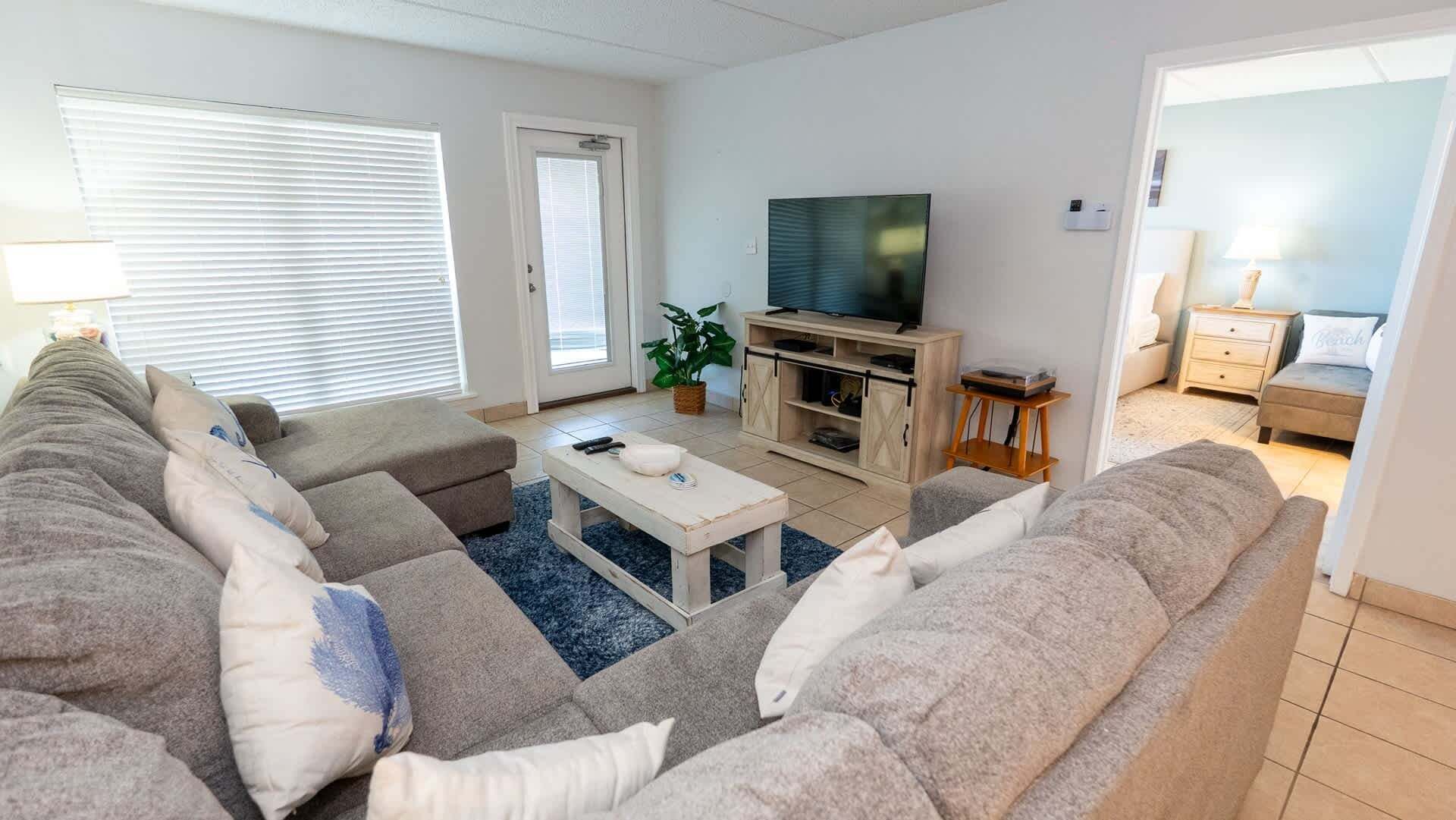 Een woonkamer met een bank, een televisie, een bijzettafeltje en een plant.