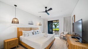 Una camera d'albergo moderna con un letto grande, un ventilatore a soffitto, una televisione e un balcone con vista.
