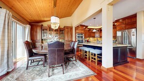 A spacious kitchen with wooden cabinets, a dining area with a large table and chairs, and a bar area with stools. - The Pointe #02 3 Bedroom Townhouse (Mammoth Lakes)