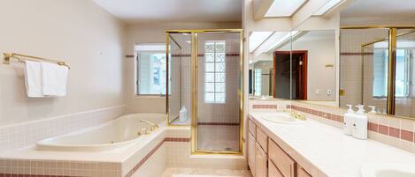 Une salle de bain moderne dotée d’une grande baignoire, de deux lavabos et d’une douche à l’italienne.