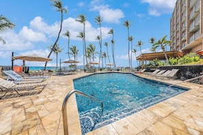 A pool area with lounge chairs and umbrellas, surrounded by palm trees and a building. - Mana Kai Maui Resort, #706c 2 Bedroom Condo (Kihei)