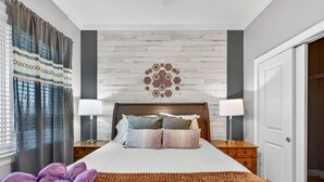 A hotel room with a bed, two bedside tables with lamps, a wooden headboard, a patterned wall, and a door. - Venus Unit 152 2 Bedroom Condo (Gatlinburg)