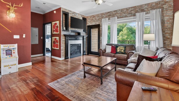 A living room with a fireplace, leather sofa, and a game console. - Venus Unit 152 2 Bedroom Condo (Gatlinburg)