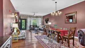 A spacious living room with a dining area, hardwood floors, a fireplace, and a view of the outdoors. - Venus Unit 152 2 Bedroom Condo (Gatlinburg)