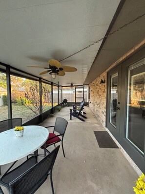 A covered patio with a table and chairs, a ceiling fan, and a view of the backyard. - Little Joe’s Cottage (Cocoa)
