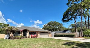 A residential house with a garage, a front yard with a lawn, and a wooden fence. - Little Joe’s Cottage (Cocoa)