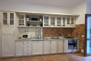 A kitchen with white cabinets, a microwave, a stove, and a sink. - Old Ghetto Charm. Sleeps 5. Ancient Ruins View (Rome)