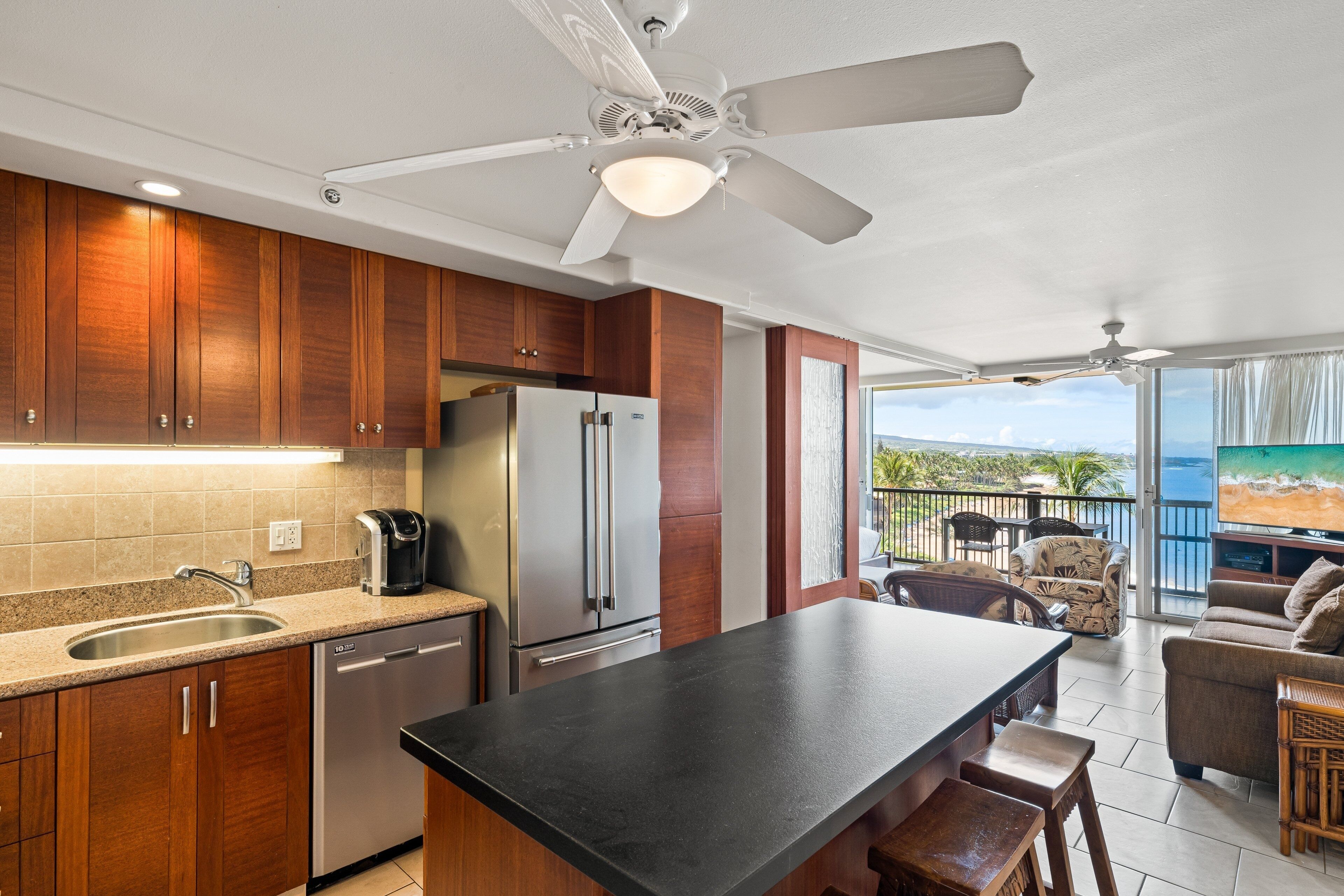 A kitchen with wooden cabinets, a stainless steel refrigerator, a coffee maker, and a large island.