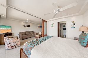 A hotel room with a bed, a sofa, a chair, a television, and a ceiling fan. - Mana Kai Maui Resort, #706a 1 Bedroom Condo (Kihei)
