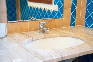 Ein Badezimmer mit Waschbecken, Spiegel und blauen Fliesen mit Muster.