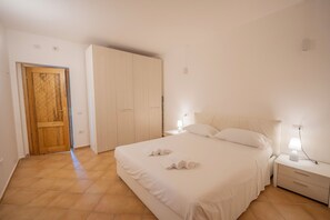 Ein Schlafzimmer mit einem Bett, Nachttischen, einem Kleiderschrank und einer Tür.