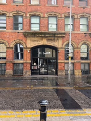 A brick building with arched windows and a sign for 'The James' restaurant. - Spacious 2BR • Workspace • Duplex • City Centre (Manchester)