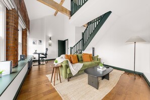 Ein großzügiger Wohnbereich mit einem grünen Sofa, einem Couchtisch und einer Treppe.
