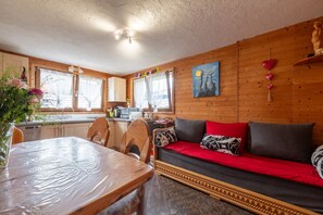 Un interior de madera con mesa de comedor, sofá y zona de cocina.