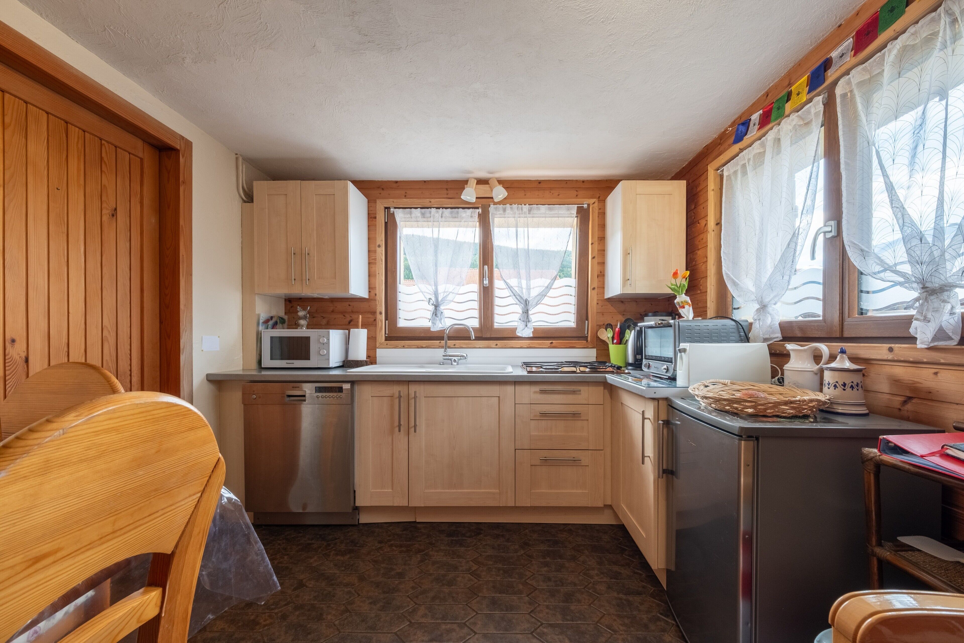 Une cuisine compacte avec des meubles en bois, un four à micro-ondes, un évier et un petit réfrigérateur.