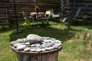 Una mesa de piedra con rocas, una valla de madera y mobiliario de exterior en un jardín.