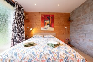 Un dormitorio con una cama grande, un cuadro en la pared, paneles de madera y una pared de piedra.