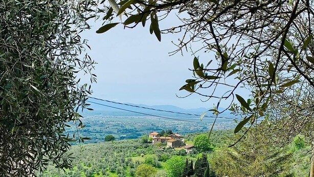 A patio with wicker furniture, a red wooden fence, and a view of a green landscape with buildings in the distance. - Tuscany natural stone house with fireplace & panorama - quiet near Vinci, close to Florence (Mezzana)