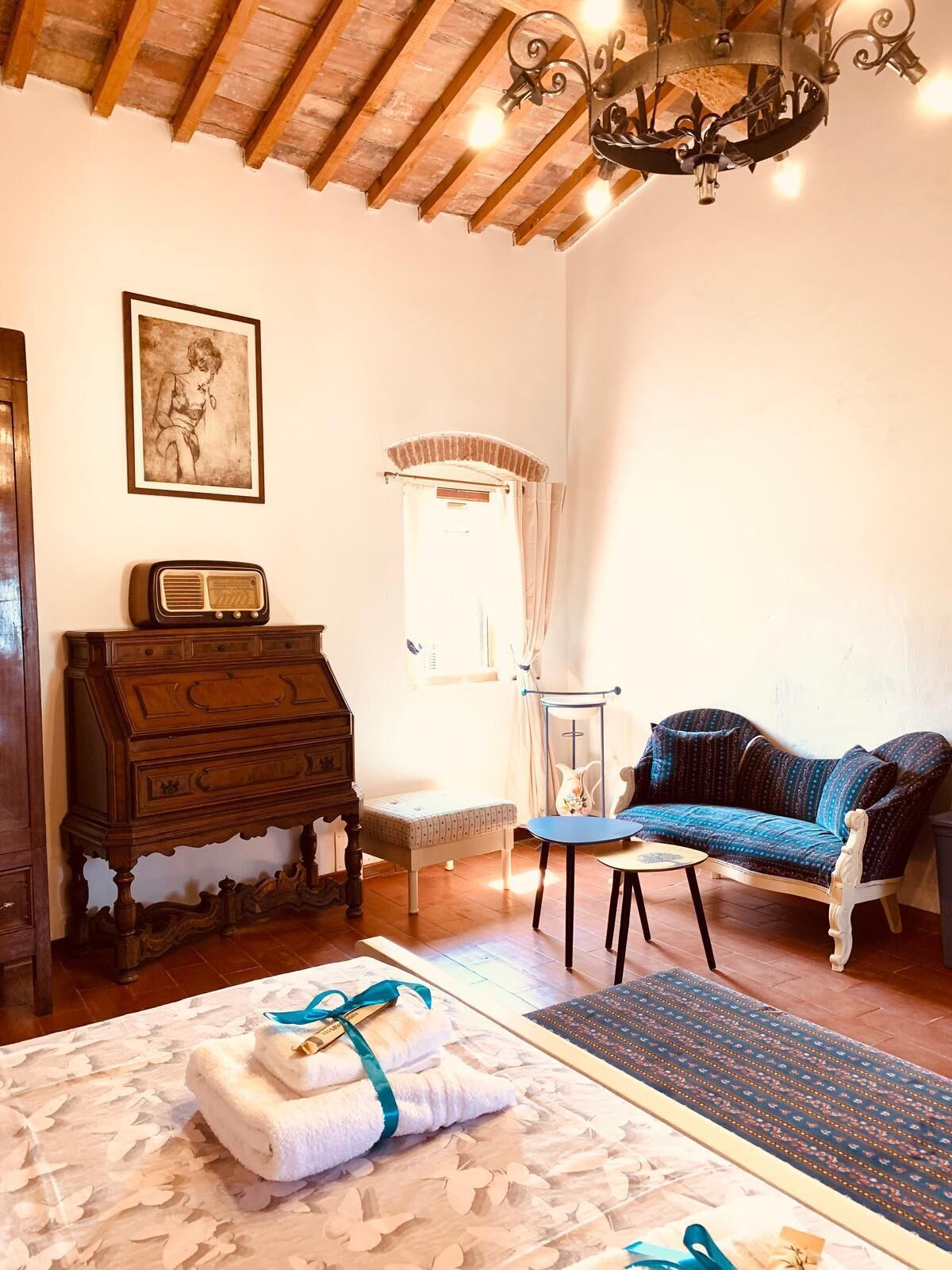 Una stanza con una cassettiera in legno, un divano blu, un tavolino, un lampadario e un quadro appeso al muro.