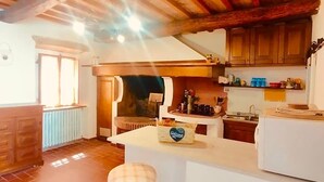 A kitchen with a central island, wooden cabinets, a radiator, and a window. - Tuscany natural stone house with fireplace & panorama - quiet near Vinci, close to Florence (Mezzana)