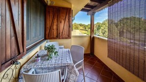Un balcon avec une table et des chaises, un pot de fleurs et une vue sur le paysage.