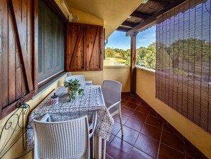 Ein Balkon mit Tisch und Stühlen, einem Blumentopf und Blick auf die Landschaft.