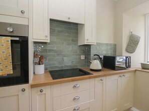 A kitchen with white cabinets, a black kettle, a toaster, and a knife block. - The Barn at Grasmere (Ambleside)