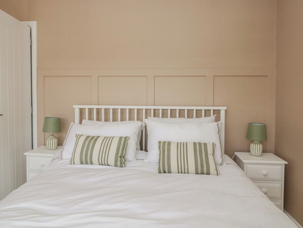 A bedroom with a white bed, two nightstands, and a closed door. - The Barn at Grasmere (Ambleside)
