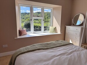 A bedroom with a large window, a bed, a dresser, and a mirror. - The Barn at Grasmere (Ambleside)